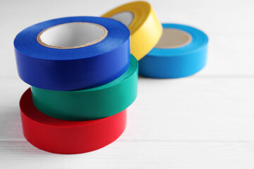 Colorful insulating tapes on white wooden table, space for text