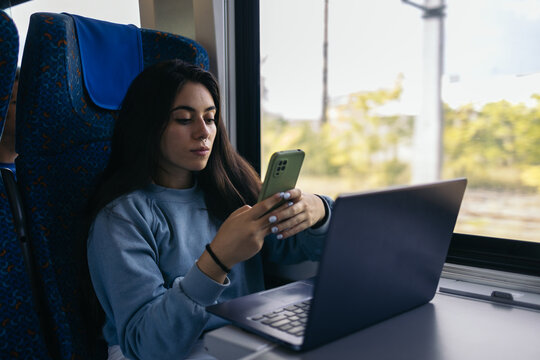 Young woman using laptop and smartphone on the train