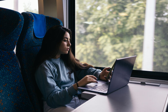 Young woman using laptop and smartphone on the train