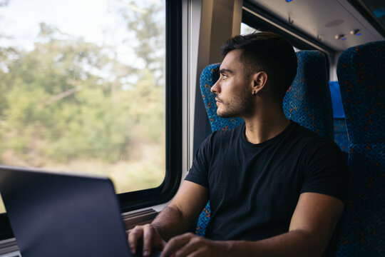 Young man working remotely with laptop on the train