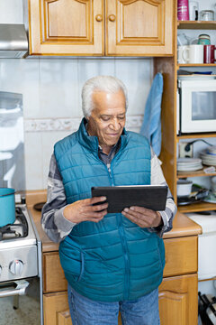 Smiling senior on video call at house with a digital tablet