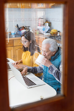 Old man drinking coffee from cup while watching videos on notebook