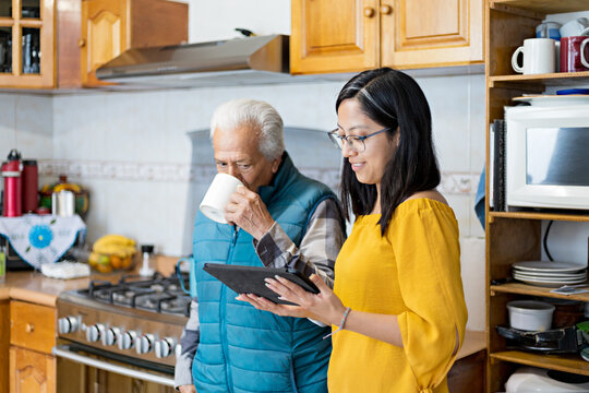 Senior drinking tea, waiting girl to connect tablet for video calls
