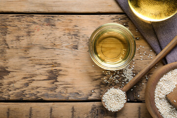 Sesame oil and seeds on wooden table, flat lay. Space for text