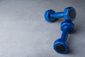 Blue vinyl dumbbells on light grey table. Space for text