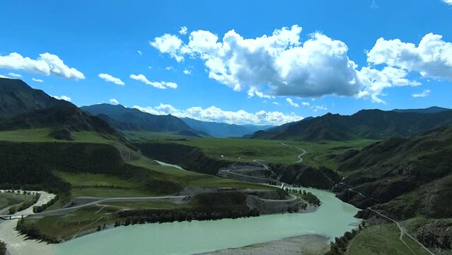 Mountain valley with confluence of two rivers of turquoise color. Drone flying above alpine landscape.