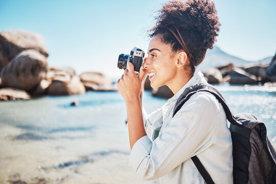 Photographer, woman and camera at beach for travel vacation or holiday in summer sun. Tourist, happy photography and black woman shooting pictures on sea sand for outdoor lifestyle in sunshine