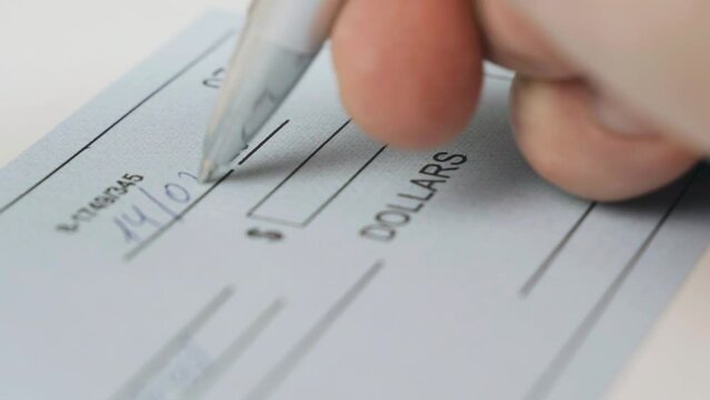 A man writes a bank check for 5,000 dollars. Close-up. Business concept.