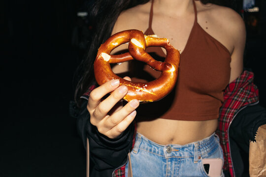 Young woman eating a pretzel at night