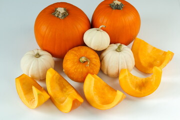 Whole orange and white pumpkins and sliced pieces on the table. Step 2. Step-by-step instructions. Preparation of pumpkin for cooking candied fruits.
