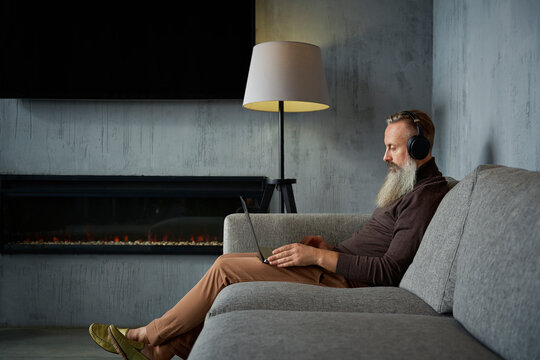 Senior businessman with headphone working on laptop.