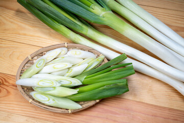 Fresh Japanese Bunching Onion on bamboo basket, Green Japanese spring onions on wooden background.