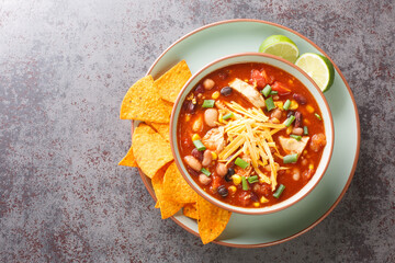 Chicken taco soup cooked in fragrant broth with beans, corn, tomatoes served with lime and tortilla...