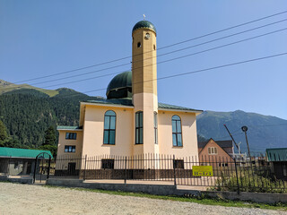 Arkhyz, Karachay-Cherkessia, Russia - August 25, 2022: View of the main mosque in the village of Arkhyz against the backdrop of the Caucasus Mountains