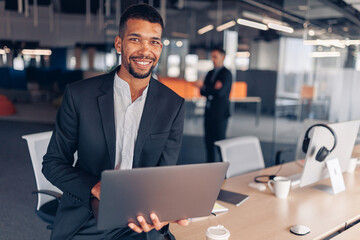 Portrait of african businessman with laptop looking in camera and smiling