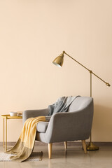 Stylish armchair with plaid and floor lamp near color wall
