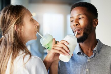 Restaurant, date and couple drinking a milkshake together while at a romantic summer adventure. Happy, love and interracial man and woman enjoying a smoothie at a cafe or coffee shop in the city.