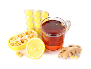 Pills for sore throat, glass cup of tea, lemon and ginger on white background