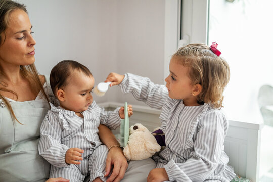 little girl combing her baby brother in bedroom