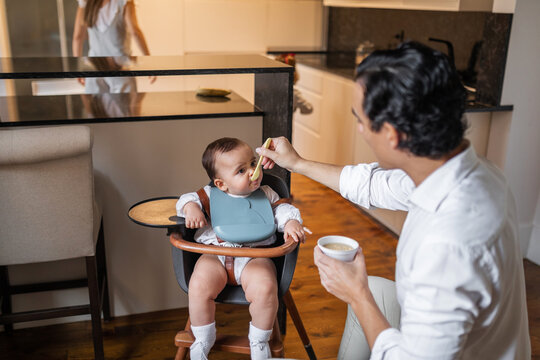 young father feeding his baby at home