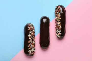 Tasty chocolate eclairs on color background