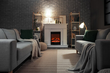 Interior of dark living room with fireplace, sofas and glowing lamps