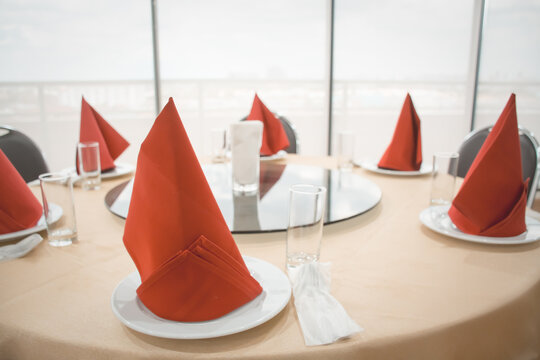 Round Table With A Oldrose Tablecloth, Glassware, Cutlery And Red Napkins In A Modern Restaurant Or The Banquet Room Of A Luxury Hotel. Catering Services For An Event Party. Covid Protection Measures.