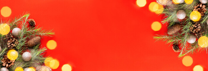 Festive composition with fir branches and golden garland light on red background. Merry Christmas...