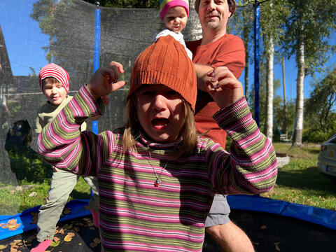 Farher and three children jumping on a batut