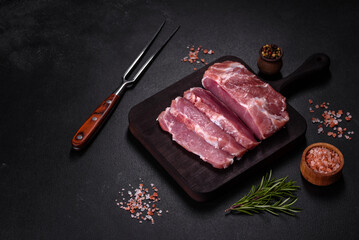 Fresh piece of raw pork with spices, salt and herbs on a wooden cutting board