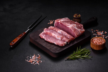 Fresh piece of raw pork with spices, salt and herbs on a wooden cutting board