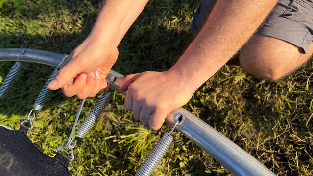 Man's hands with a tool unhooking strings