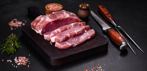 Fresh piece of raw pork with spices, salt and herbs on a wooden cutting board