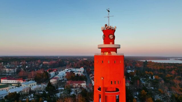 Aerial view in front of the sunlit water tower revealing the church, sunrise in Hanko city, Finland - reverse, pan, drone shot