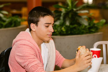 Teen making weird faces at burger in restaurant
