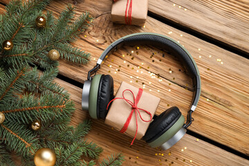 Composition with modern headphones, Christmas gifts and fir branches on wooden background