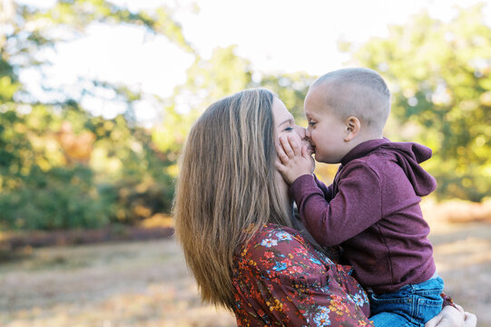 Toddler boy squishing mothers cheeks and giving her a kiss