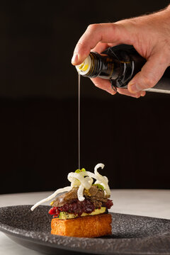 Crop cook pouring oil on deer tartar brioche