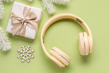 Composition with modern headphones, Christmas gift and fir branches on color background
