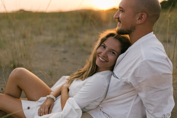 Close up portrait of young couple in love sitting at the beach