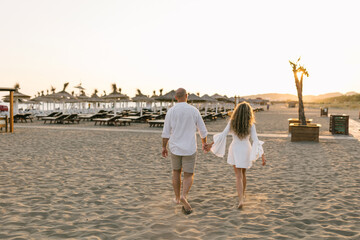 Young couple walking at sandy beach at sunset