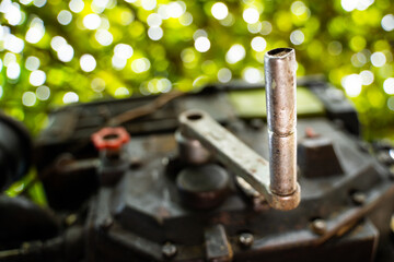 A crooked starter is inserted into the engine of a walk-behind tractor close-up on a blurred bright...