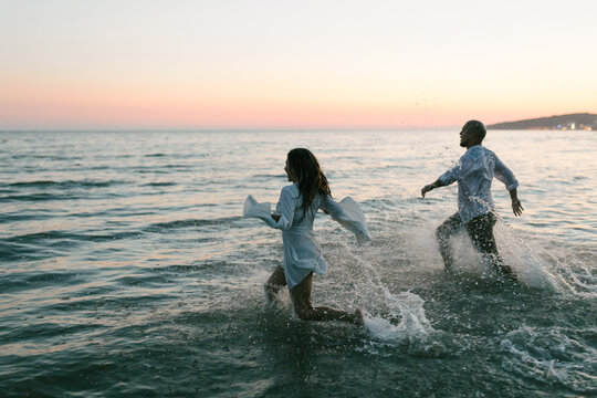 Happy young couple running into the water