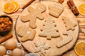 Board with tasty Christmas cookies and ingredients on wooden background, closeup