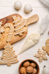 Composition with tasty Christmas cookies, bag of cream and walnuts on light wooden background, closeup