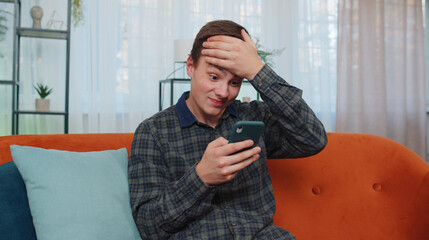 Portrait of teenager adult man use smartphone typing browsing, loses becoming surprised sudden...