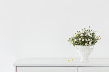 white flowers in white ceramic vase in white interior