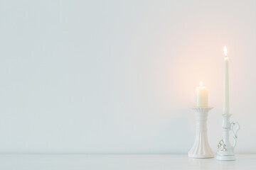 white burning candles on background white wall