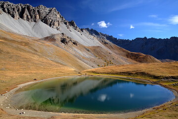 Souliers lake located above Izoard Pass (after one hour hike from Casse deserte car park), with reflections of mountain range and Autumn colors, Queyras Regional Natural Park, Southern Alps, France