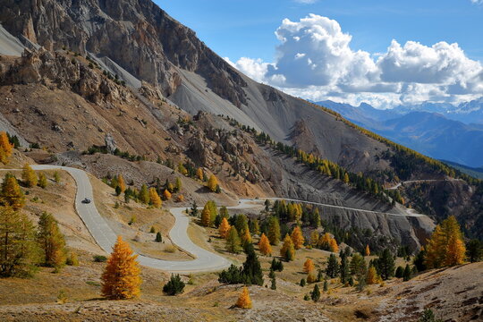 Colorful Autumn scenery with the Southern side of Izoard pass, the landscape called Casse deserte (a lunar and rocky circus) and a winding road, Queyras Regional Natural Park, Southern Alps, France